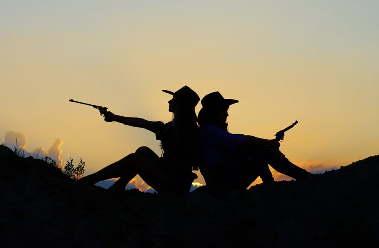 Silhoutte of Two Cowgirl Friends Holding Guns